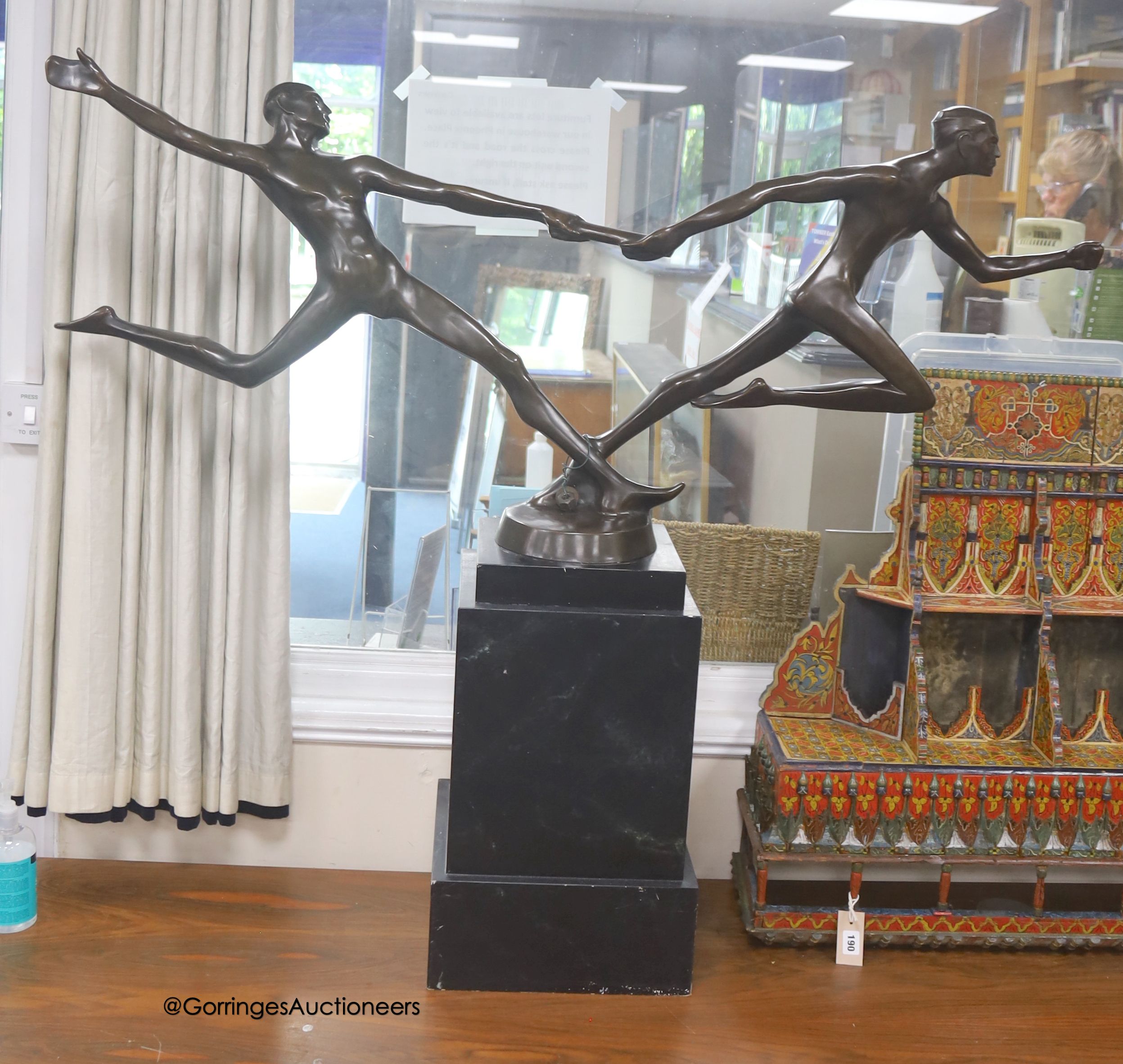 A large bronze of baton runners on faux marble base